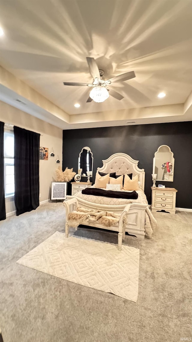 bedroom with a tray ceiling, ceiling fan, and carpet flooring