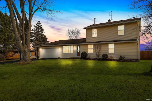 back house at dusk featuring a garage and a lawn