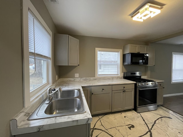 kitchen featuring gray cabinets, stainless steel gas range oven, and sink