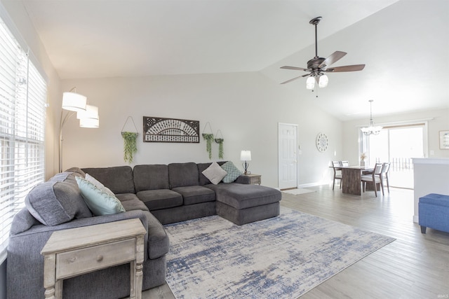 living room with hardwood / wood-style floors, ceiling fan with notable chandelier, and vaulted ceiling