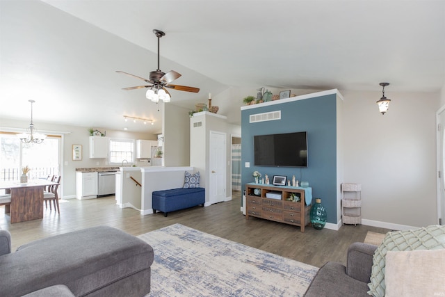 living room featuring lofted ceiling, wood-type flooring, and ceiling fan with notable chandelier