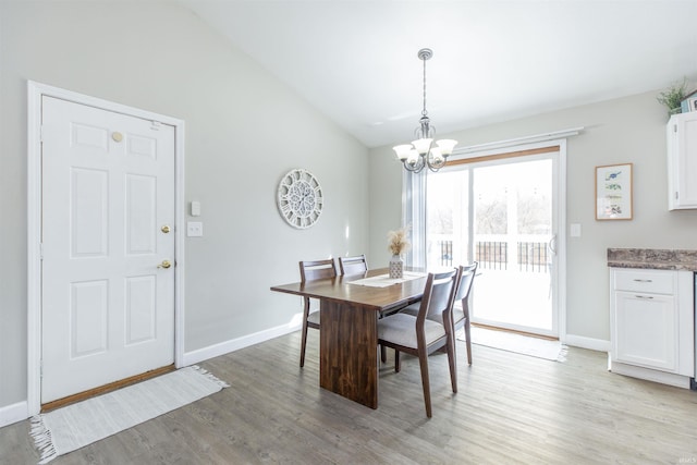 dining area featuring a notable chandelier, vaulted ceiling, and light hardwood / wood-style floors