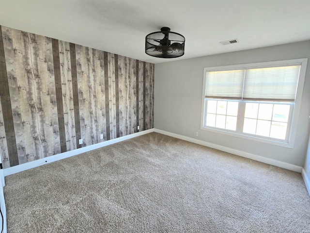 carpeted empty room with wood walls