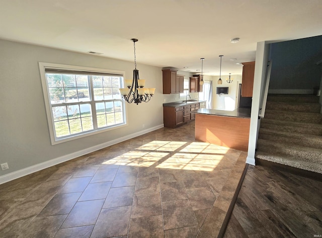 kitchen featuring decorative light fixtures, a chandelier, sink, and kitchen peninsula