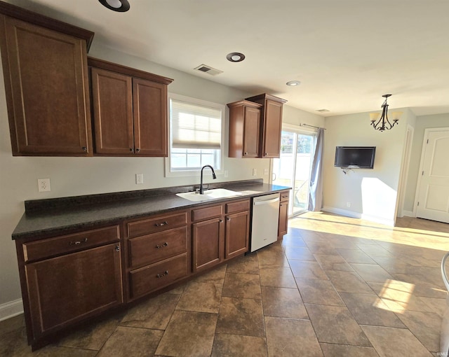 kitchen featuring stainless steel dishwasher, sink, and hanging light fixtures