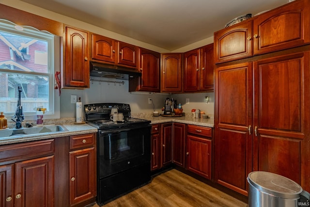 kitchen featuring black electric range oven, hardwood / wood-style floors, sink, and light stone countertops