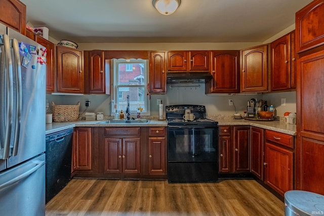 kitchen featuring ventilation hood, hardwood / wood-style flooring, sink, and black appliances