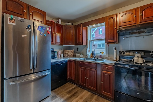 kitchen featuring wood-type flooring, sink, and black appliances