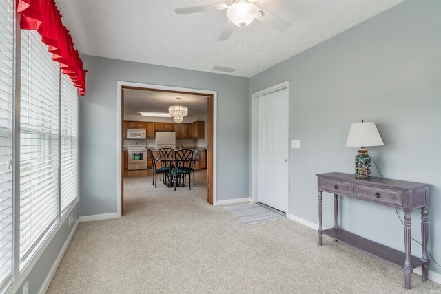 interior space with light colored carpet and ceiling fan with notable chandelier