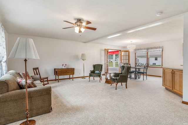 carpeted living room with ceiling fan with notable chandelier