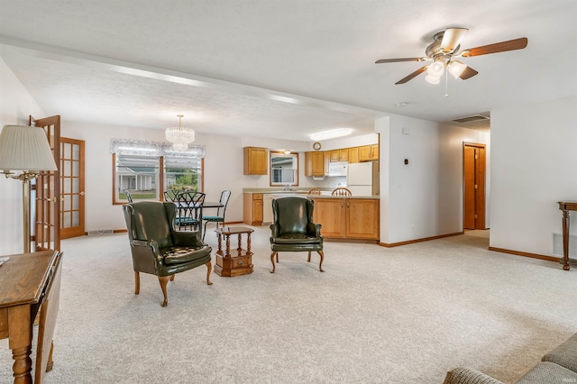 living room featuring ceiling fan with notable chandelier and light colored carpet