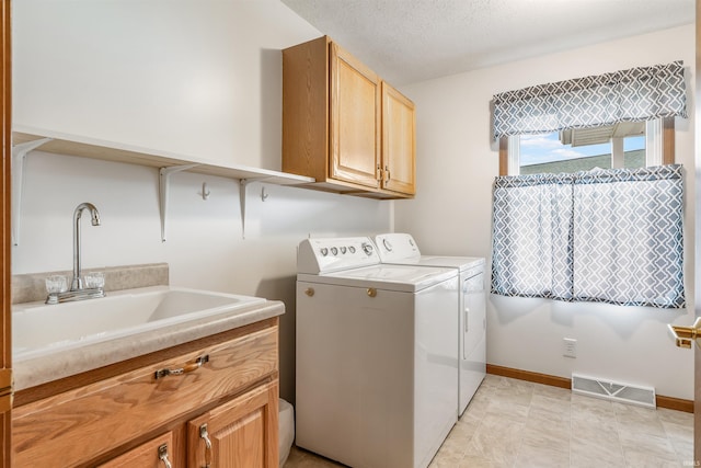 washroom with sink, a textured ceiling, cabinets, and washing machine and clothes dryer