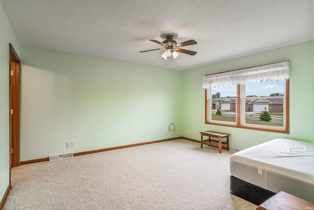 unfurnished bedroom featuring a textured ceiling, ceiling fan, and carpet