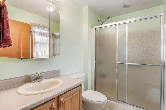 bathroom with vanity, an enclosed shower, a textured ceiling, and toilet