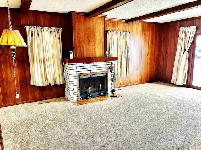 unfurnished living room featuring a fireplace, wood walls, carpet flooring, a textured ceiling, and beam ceiling