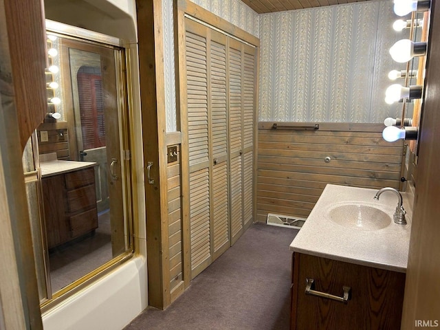 bathroom with vanity, shower / bath combination with glass door, and wood walls