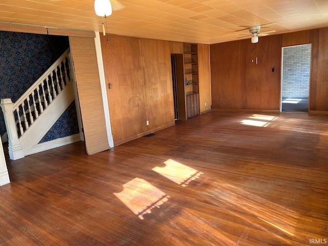 spare room with ceiling fan, dark hardwood / wood-style floors, and wood walls