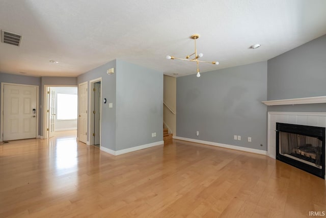 unfurnished living room with a tile fireplace and light hardwood / wood-style flooring