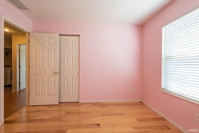 unfurnished bedroom featuring washer / dryer, light wood-type flooring, and a closet