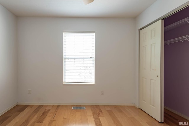 unfurnished bedroom with a closet, light hardwood / wood-style floors, and multiple windows