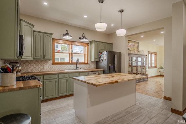 kitchen with butcher block countertops, sink, appliances with stainless steel finishes, a center island, and decorative backsplash