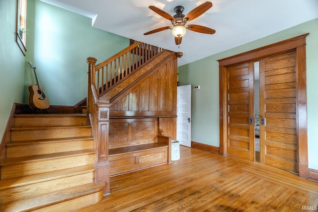 stairs featuring hardwood / wood-style floors and ceiling fan