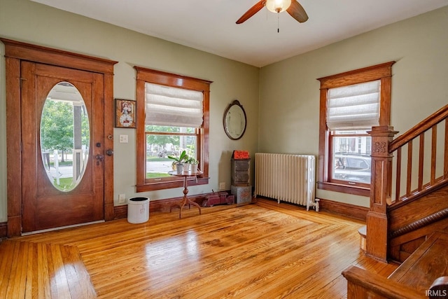 foyer entrance with a healthy amount of sunlight, radiator, ceiling fan, and light wood-type flooring