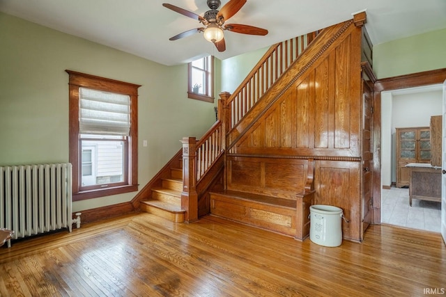 stairs featuring ceiling fan, radiator heating unit, and wood-type flooring