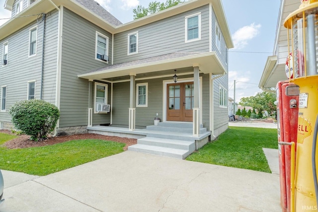 view of front facade with cooling unit, a porch, a front yard, and french doors