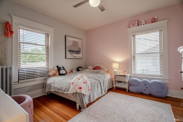 bedroom with ceiling fan, wood-type flooring, and radiator