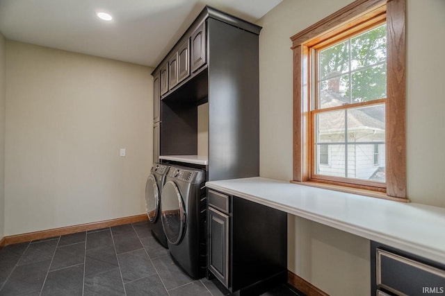 clothes washing area featuring cabinets, washer and dryer, and dark tile patterned floors