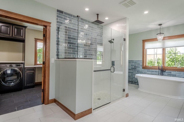 bathroom with a healthy amount of sunlight, washer / clothes dryer, tile walls, and plus walk in shower