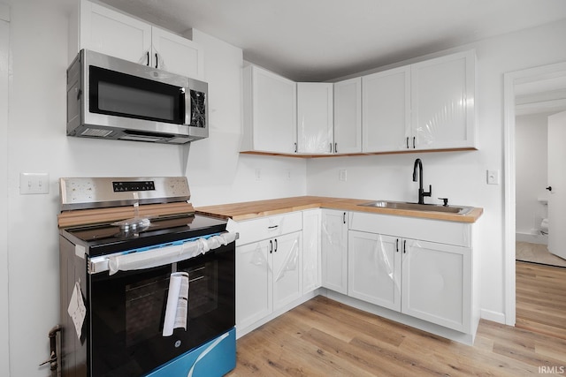 kitchen featuring stainless steel appliances, light hardwood / wood-style floors, sink, and white cabinets