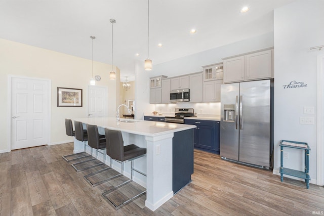 kitchen featuring decorative light fixtures, light hardwood / wood-style flooring, stainless steel appliances, and a kitchen breakfast bar