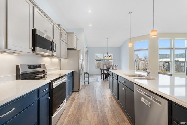 kitchen with pendant lighting, sink, stainless steel appliances, and light wood-type flooring