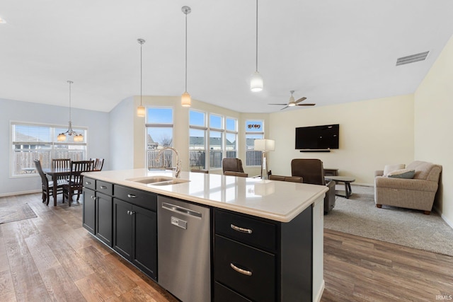 kitchen featuring a kitchen island with sink, sink, pendant lighting, and stainless steel dishwasher