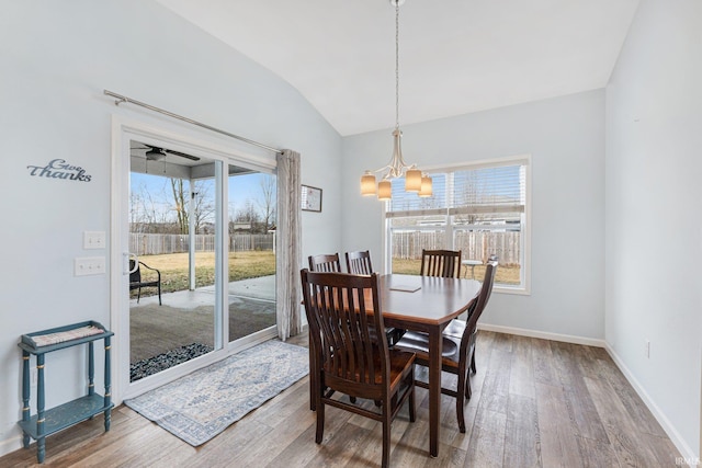 dining space with lofted ceiling, hardwood / wood-style flooring, a wealth of natural light, and an inviting chandelier