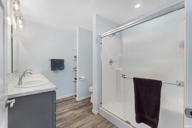 bathroom featuring toilet, a shower with shower door, a textured ceiling, vanity, and hardwood / wood-style flooring