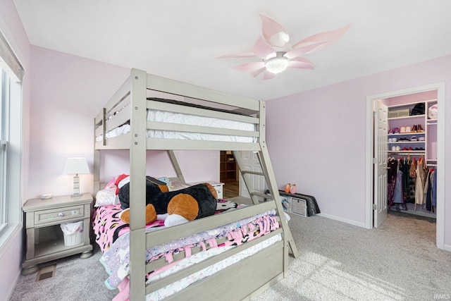 bedroom featuring a walk in closet, light carpet, ceiling fan, and a closet