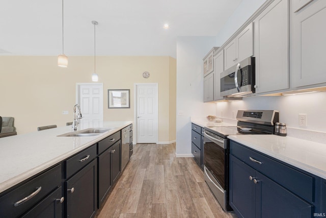 kitchen with appliances with stainless steel finishes, decorative light fixtures, blue cabinets, sink, and light hardwood / wood-style flooring