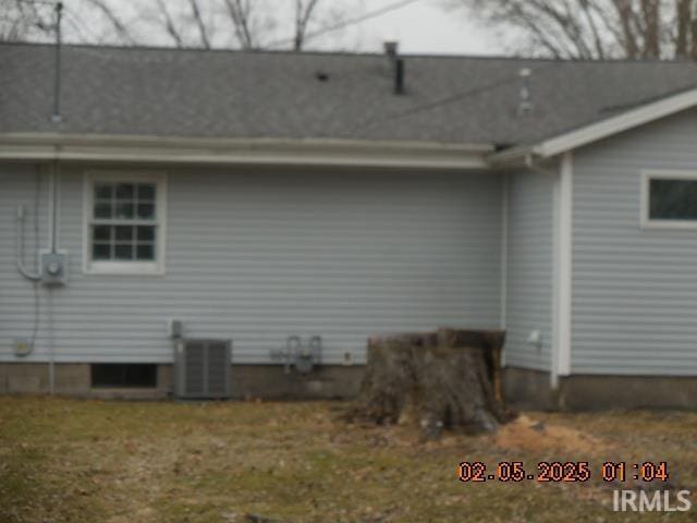 rear view of property featuring central AC unit and a yard