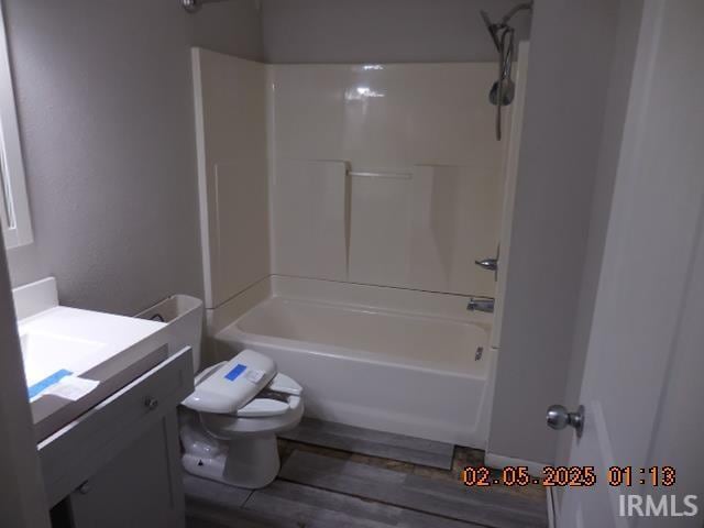 full bathroom featuring hardwood / wood-style flooring, vanity, tub / shower combination, and toilet