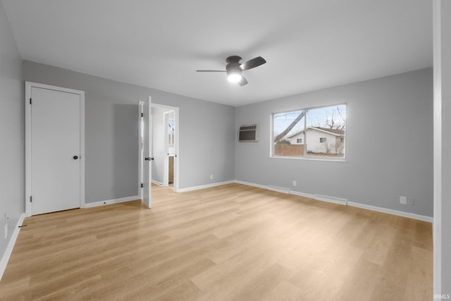 spare room with ceiling fan, an AC wall unit, and light wood-type flooring