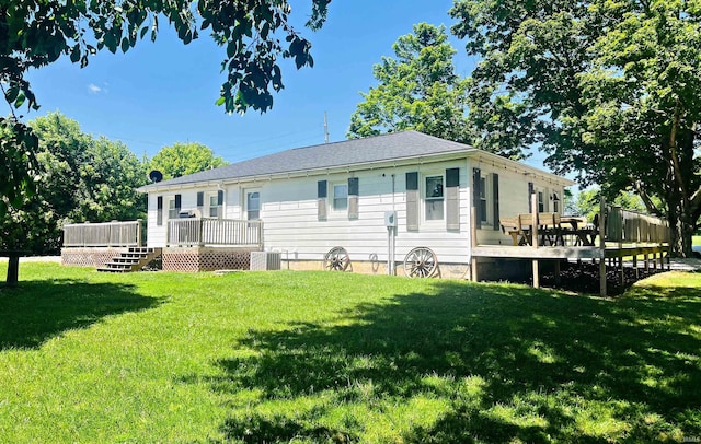 rear view of house featuring a wooden deck, a yard, and central AC