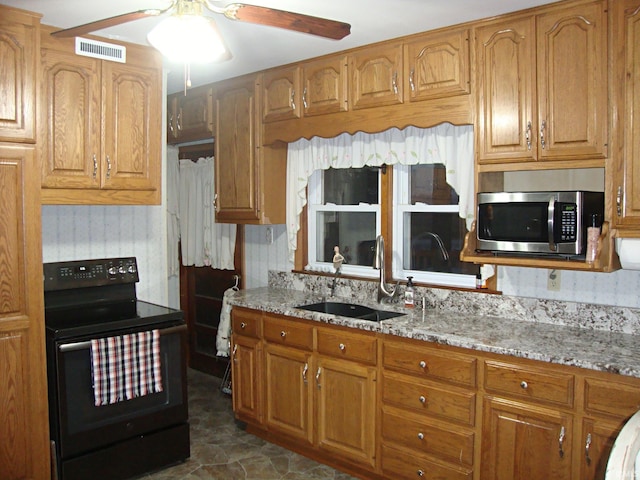 kitchen featuring black range with electric stovetop, light stone countertops, sink, and ceiling fan