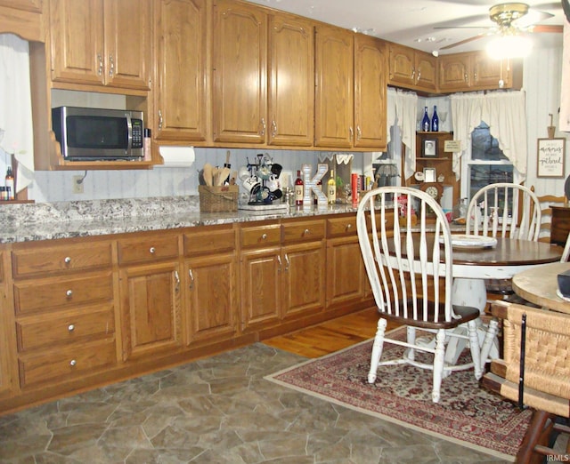 kitchen featuring light stone countertops, ceiling fan, and decorative backsplash