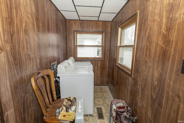 clothes washing area featuring washing machine and clothes dryer and wooden walls