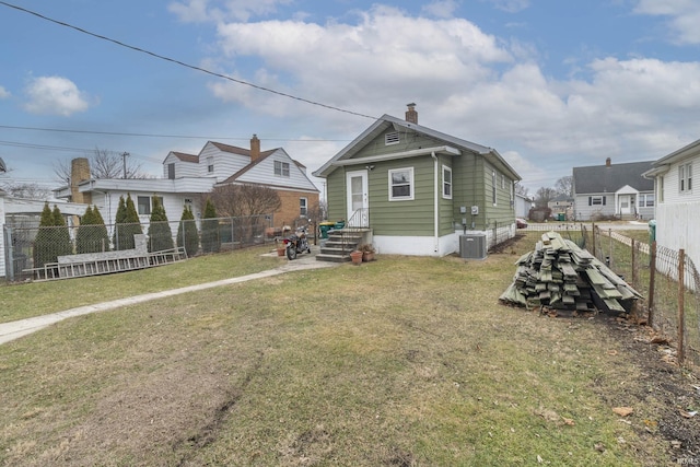 rear view of property with a yard and central air condition unit