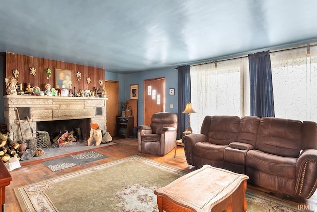 living room with wood-type flooring and a stone fireplace