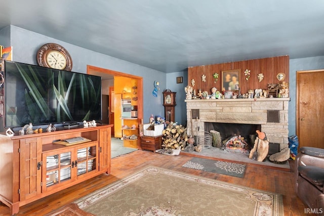 living room with hardwood / wood-style flooring and a stone fireplace